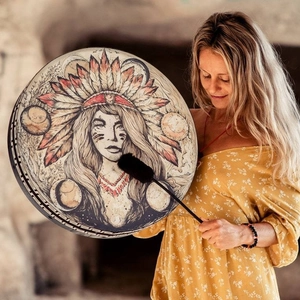 Ethnic shaman drum with native Indian woman portrait held by a woman in a rustic cave