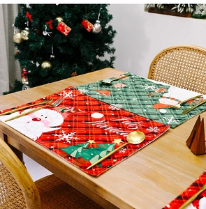 Detailed view of red and green plaid Christmas placemats with Santa and snowman motifs