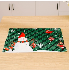 Detail of green plaid Christmas placemat with snowman and robin on a wooden table