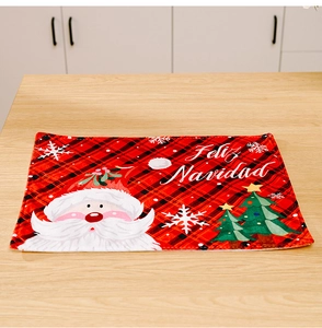 Detail of red and black plaid Christmas placemat featuring Santa Claus and Feliz Navidad text