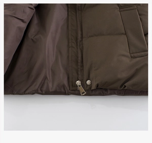 Detail of kids warm brown vest showing zipper, metal button and pocket stitching quality