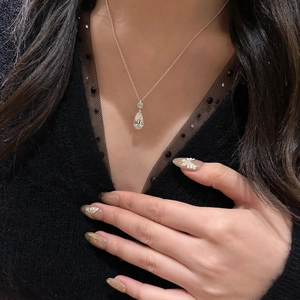 Close-up of sparkling teardrop zircon pendant necklace worn on a black V-neck sweater