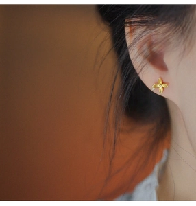 Close-up of elegant golden four-petal flower earrings with zircon on a model