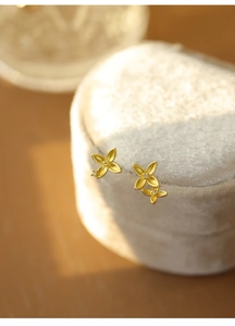 Detailed macro of golden four-leaf flower earrings with diamonds on a velvet box