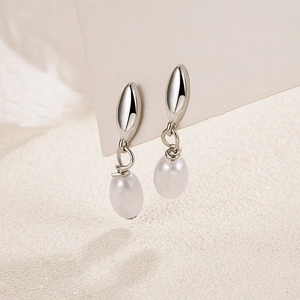 Elegant teardrop pearl drop earrings with silver leaf metal design on a neutral background