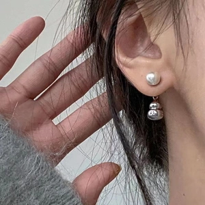 Minimalist pearl stud earring with hollow gourd pendant in silver finish on ear