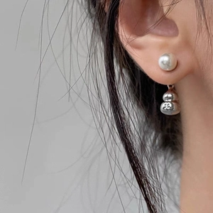 Macro shot of silver gourd pearl earrings showing elegant design on a model