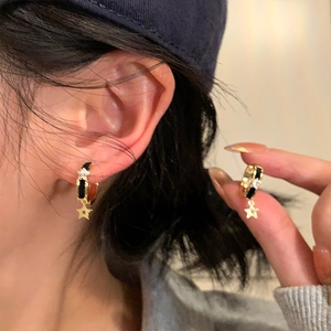 Détail de boucles d'oreilles créoles étoile en émail noir avec un zircon brillant