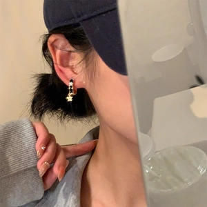 Gros plan de boucles d'oreilles dorées avec émail noir et pendentif étoile orné de cristaux