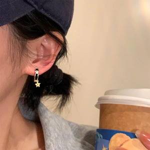 Boucles d'oreilles créoles étoile noire et dorée portées avec décor café chic