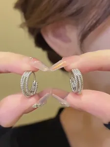Close-up of silver multi-layer C-shaped hoop earrings with micro-set sparkling crystals