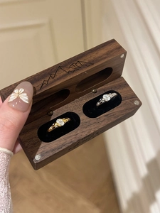 Oval cut stone rings in a walnut wood jewelry box with mountain line engraving detail
