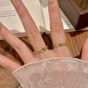 Detail of vintage gold ring set with oval moissanite stone and hammered metal band