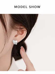 Model wearing a matte silver heart earring with starburst engraving detail