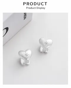 Macro shot of silver heart stud earrings with matte finish and engraved starburst detail