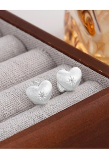 Macro shot of brushed heart earrings with starburst engraving and small zircon detail