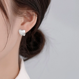 Elegant matte silver heart earrings with star-engraved zircon on a fashion model