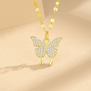 Elegant gold butterfly necklace with crystal wings on minimalist beige card background
