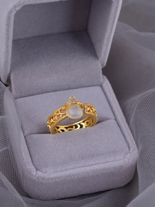 Detail of gold hollow ring with white jade gourd and diamonds in a velvet box