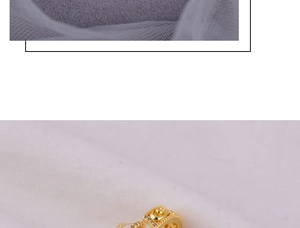 Detail of golden pig earrings with zircon embellishments on white textured fabric