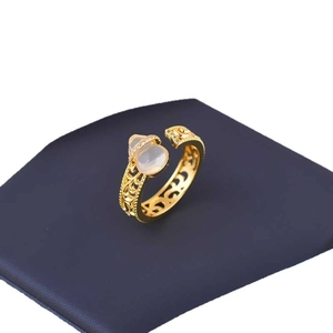 Luxury gold hollow gourd ring with translucent gemstone and zircon accents on blue mat
