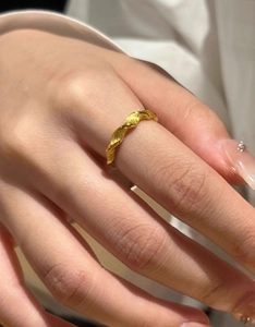 Detailed close-up of a gold Mobius twist ring with a refined matte brushed metal texture