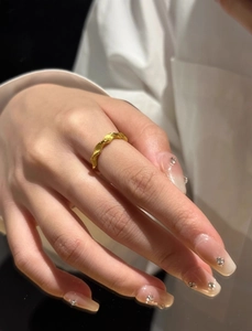 Detailed view of matte gold Mobius ring with wave twist design on a model's hand