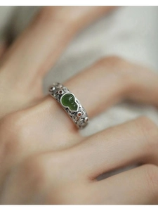 Macro detail of Hetian jade gourd ring with vintage silver filigree and red accents
