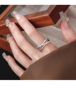 Close-up of minimalist silver X-shaped layered ring with pave crystals on hand
