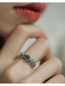 Detailed macro view of silver filigree ring with green jade gourd and red enamel accent