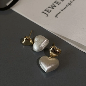 Detail of two-tone heart stud earrings with matte silver and polished gold finish