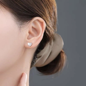 Minimalist brushed silver heart stud earring shown on model with luxury matte finish
