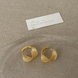 Pair of vintage gold twisted hoop earrings with mesh texture on a rippled glass tray