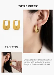 Detail of matte gold U-shaped earrings featuring a brushed metallic finish texture
