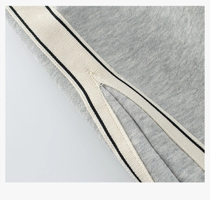 Detail of grey kids' cotton jogger pants with striped side tape and hem slit