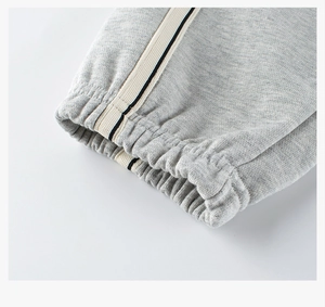 Detail of grey kids sweatpants featuring elastic cuffs and side decorative ribbon trim