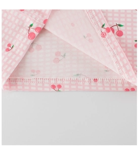 Détail de pyjama enfant à carreaux roses avec motif cerise et couture à double aiguille