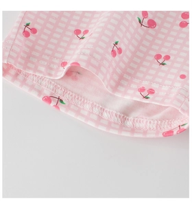 Détail de l'imprimé cerise et de l'ourlet à double couture sur vêtement enfant en coton