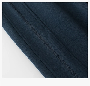 Detail of reinforced flatlock stitching on navy blue knit kids sports trousers fabric