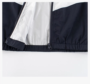 Detail of kids' black and white windbreaker with zipper and elastic hem on white background