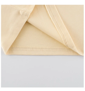 Detailaufnahme der feinen Strickstruktur und Doppelnaht am Saum des gelben Mädchen-T-Shirts