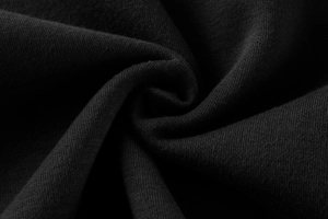 Macro shot of high-quality black cotton knit fabric with a soft texture and spiral pattern