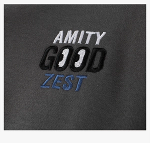 Detail showing multi-color AMITY GOOD ZEST embroidery on dark gray knitted varsity jacket