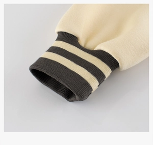 Close-up of elastic ribbed cuffs with stripe detail on a beige baseball jacket