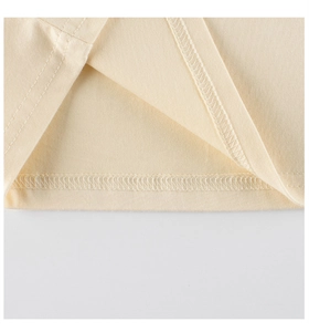 Detail of flat lockstitch sewing and fabric texture on a cream girls' cotton t-shirt