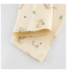 Detalle de puños de punto acanalado con estampados de conejos y hojas en pijama infantil