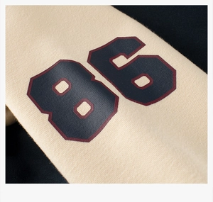 Detail of navy blue sleeve with printed number 86 on beige fleece baseball jacket