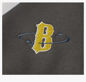 Close-up of vintage varsity jacket embroidery featuring a yellow letter B on gray fabric