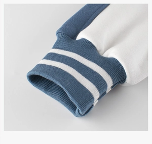 Close-up of classic ribbed cuffs with white double stripes on a navy blue varsity jacket