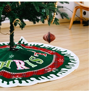 Detail of green Christmas tree skirt with plaid edges and snowflake patterns